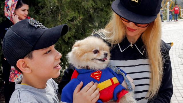 Іранська сім'я з собакою, одягненою в костюм супермена