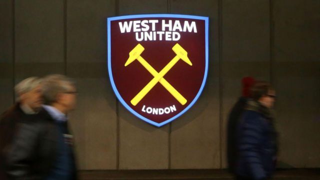 West Ham badge with people walking in front