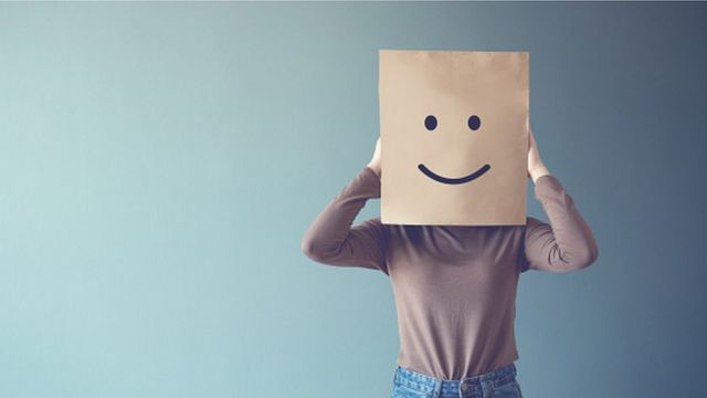 Persona con una bolsa con cara sonriente en la cabeza
