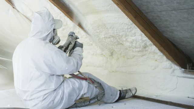 A technician sprays polyurethane foam used as roof insulation (stock photo)