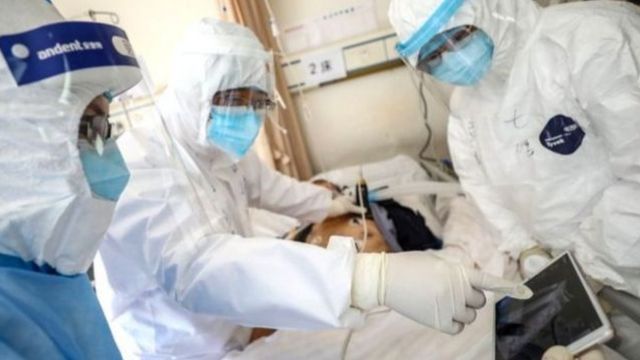 Médicos en trajes protectores tratan a un paciente en un hospital