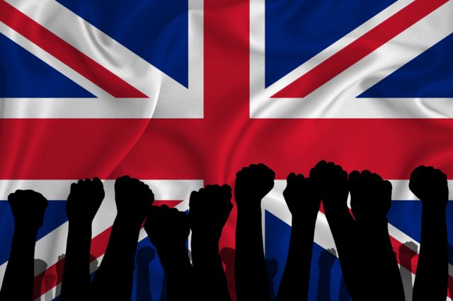 Puños en alto delante de la bandera de Reino Unido