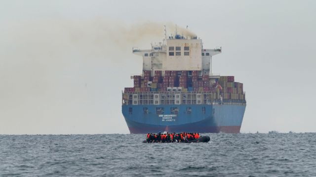 Navio diante de barco de migrantes no Canal da Mancha