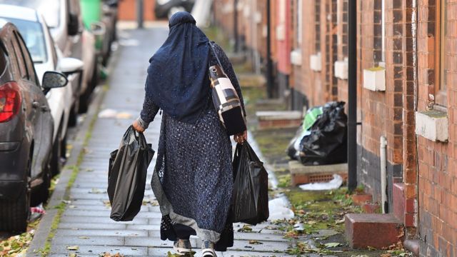 Mujer cubierta con hijab camina en una calle en Inglaterra