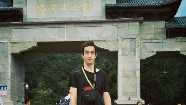 Phillip Hancock posing in front of a tourist attraction in China