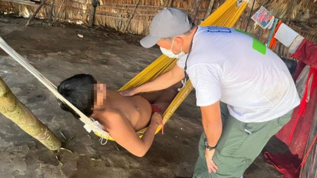 Médico examina indígena deitado em rede