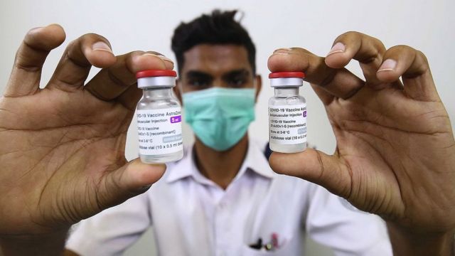 Medical workers in Pakistan holding AstraZeneca vaccine bottles