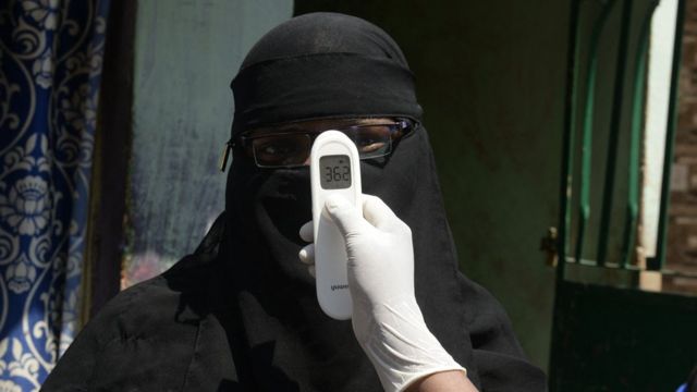 Un agent de santé vérifie la température corporelle d'une femme lors d'une enquête porte-à-porte pour surveiller les symptômes du coronavirus Covid-19 chez les résidents d'un quartier à faible revenu d'Hyderabad le 6 mai 2021.