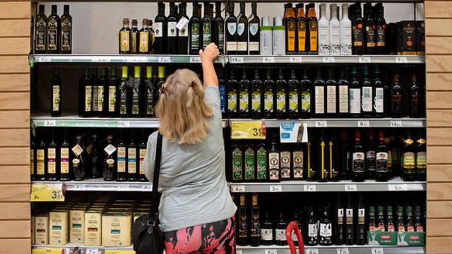 Mulher pegando azeite em supermercado