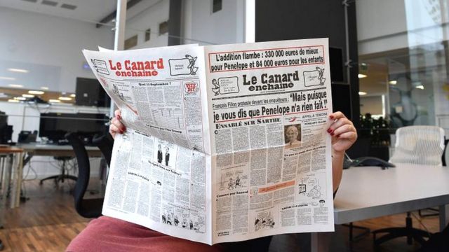 Una lectora de Le Canard Enchaîné sostiene un ejemplar del diario