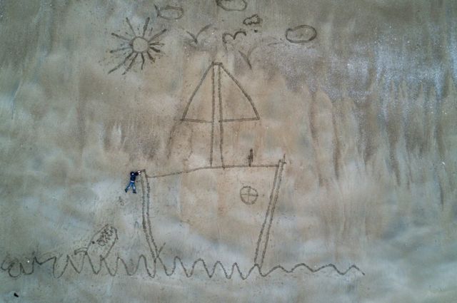 An image created in the sand representing Ugo in difficulty in the open sea