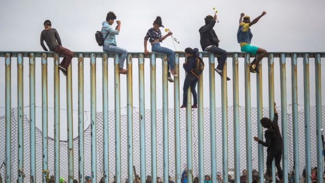 Gente saltando una valla en abril de 2018 en Tijuana, Baja California Norte, México.