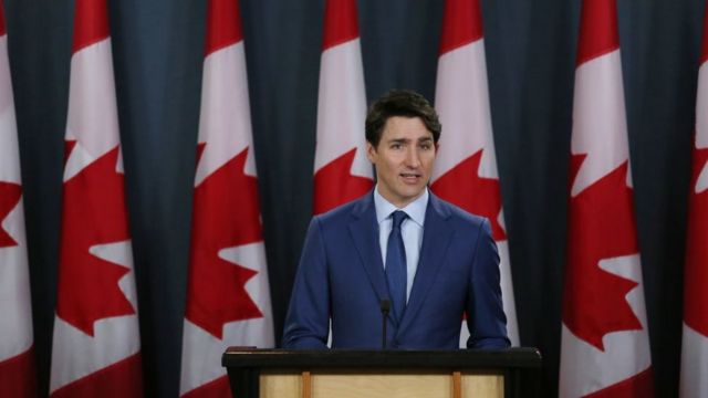 Justin Trudeau diante de bandeiras do Canadá