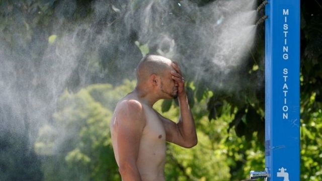 مواطن طندي يغتسل من حنفية ماء لتبريد جسمه من موجة الحر