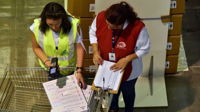 Trabajadoras del Consejo Nacional Electoral (CNE) inspeccionan los materiales de votación