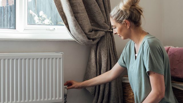 Una mujer al lado de un radiador