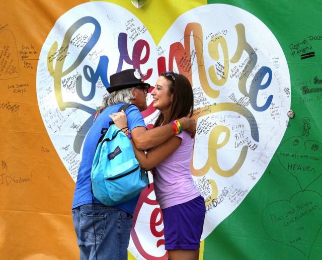 Orang berpelukan di depan lukisan hati di klub malam Pulse, Orlando, Florida, 30 September 2016.