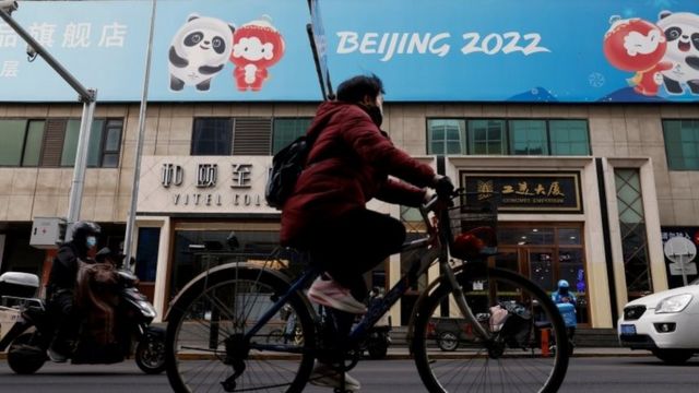 A person cycles past a Beijing 2022 sign