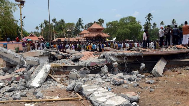People gather near damaged buildings at the spot where a massive fire broke out during a fireworks display at the Puttingal temple complex in Paravur, southern India, 10 April 2016