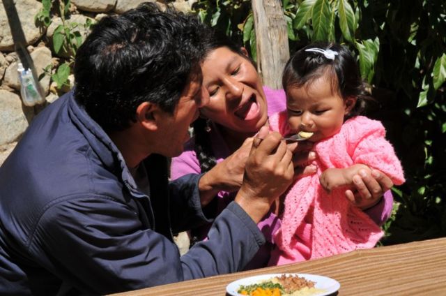 Padres alimentando a hija en Perú.