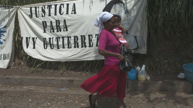 Una mujer y su hija pasan delante de un cartel en julio de 2018, en Sonsonate, en contra de las detenciones ilegales.