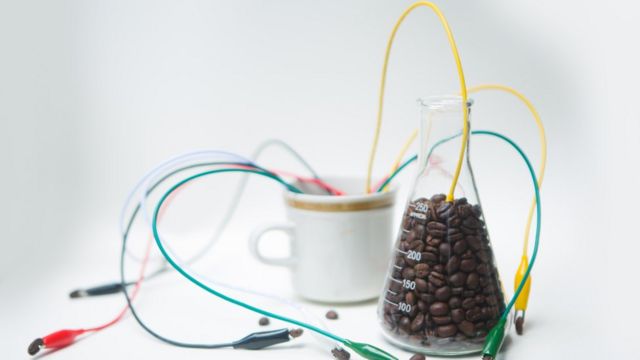 Xícara de café cheia de fios e balão de Erlenmeyer com grãos de café