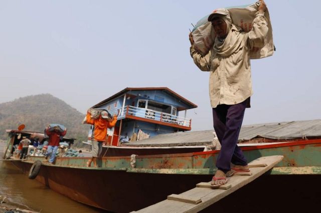 船只停泊在琅勃拉邦的东迈（Don Mai）港，老挝工人从船上搬运一袋袋大米。