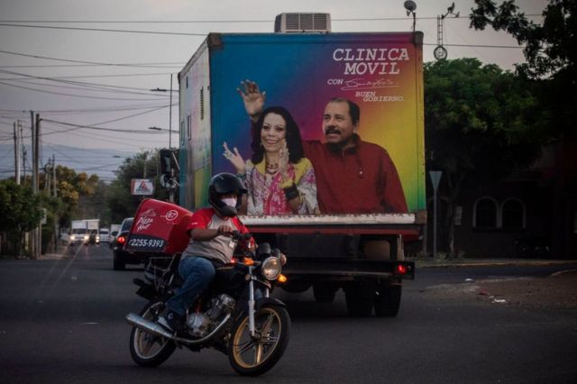 Un ciclista pasa frente a una clínica móvil del Ministerio de Salud con la imagen del presidente nicaragüense Daniel Ortega y su esposa Rosario Murillo en Managua el 18 de mayo de 2020.
