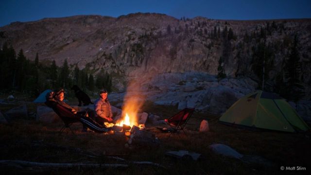 Depois de um longo dia nas montanhas, os exploradores relaxam ao redor da fogueira