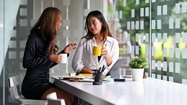 Duas mulheres conversam no ambiente de trabalho