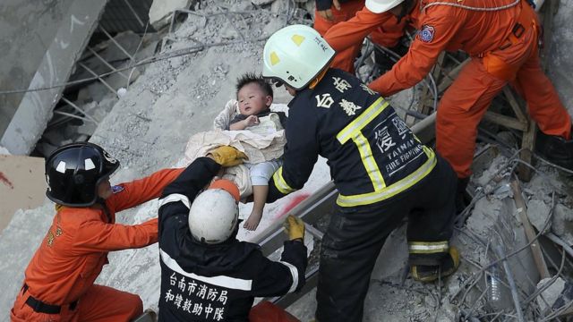 Rescue personnel help a child rescued at the site where a 17-storey apartment building collapsed during an earthquake in Tainan, southern Taiwan, February 6