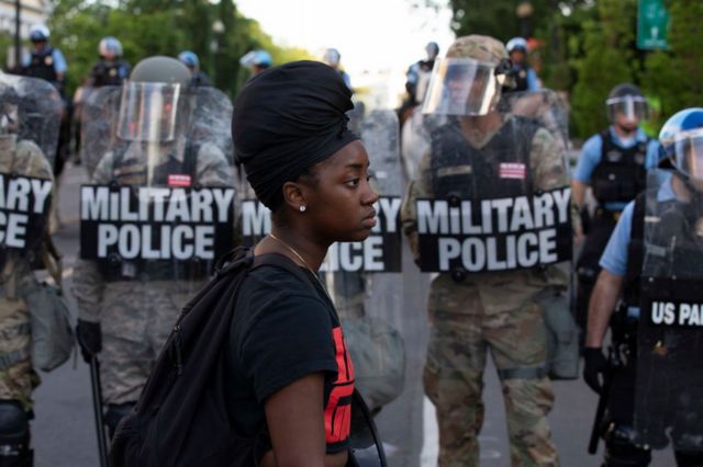 Black woman in front of police in riot gear