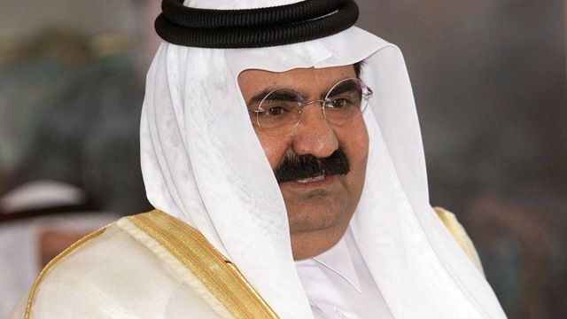 Fotografia de Hamad bin Khalifa al Thani, um homem árabe de bigode, óculos e turbante branco