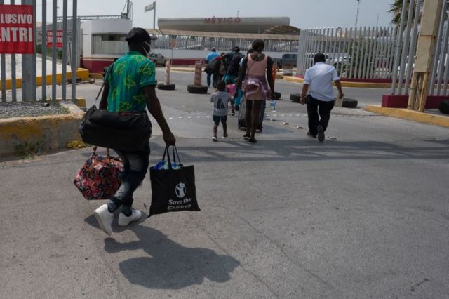 El migrante haitiano Jean Philippe Jocelin (izq.) camina acarreando sus pertenencias por Puente Internacional McAllen-Hidalgo-Reynosa para iniciar el papeleo en Reynosa, Tamaulipas, México, el 20 de mayo de 2022.