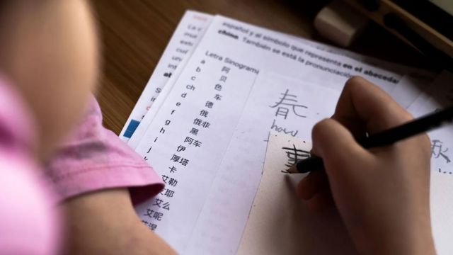 Pessoa escrevendo em um papel enquanto aprende novo idioma em ideograma chinês