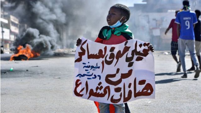 صبي سوداني يحمل لافتة خلال الاحتجاجات التي شهدتها العاصمة السودانية اليوم.