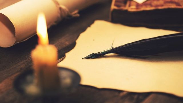 Rollos de papel, una pluma fuente y una vela