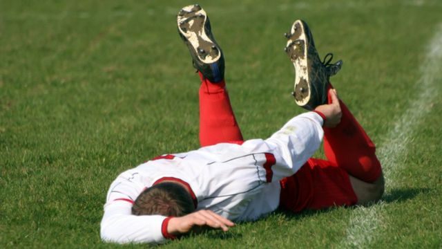 Jogador de futebol caído em campo