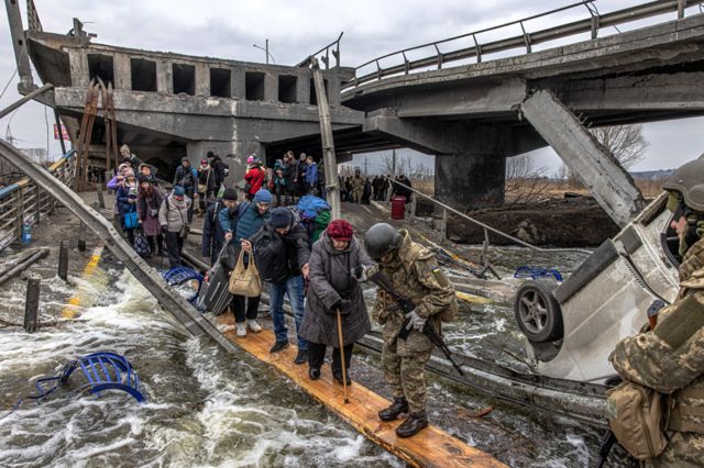 Varias personas cruzan el río a través de un puente improvisado mientras huyen de la ciudad de primera línea de Irpin, cerca de Kyiv, Ucrania, el 7 de marzo de 2022.