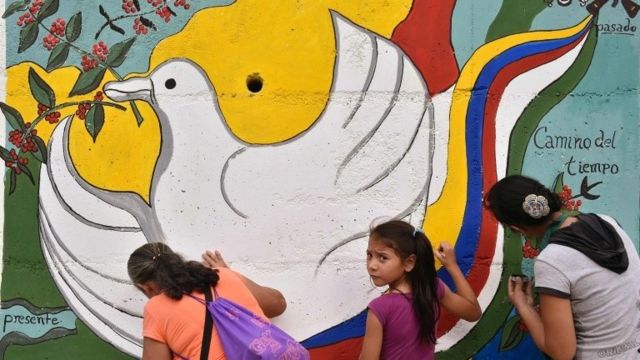 Women and a girl paint a mural alluding to peace on the road leading to Planadas, Tolima department, Colombia (August 26, 2016)