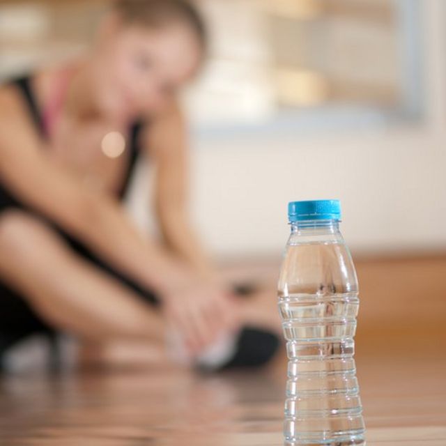 Una botella de agua delante de una mujer haciendo ejercicios