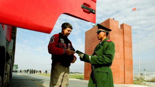 A police officer (R) checks a passport in Xinjiang (File picture October 2005)