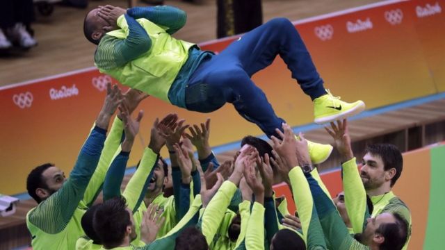 Jogadores do vôlei celebram a vitória, jogando o líbero Serginho para o alto