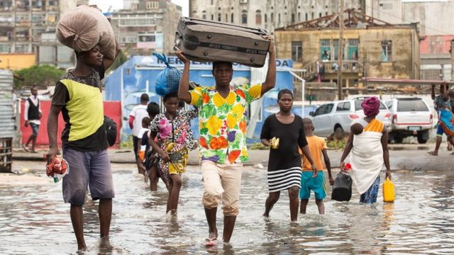 Watu wakitembea ndani ya maji ya mafuriko eneo la Praia Nova, Beira,