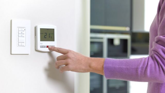 Woman adjusting the thermostat