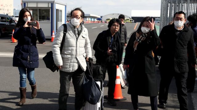 Passengers wearing face masks walk out from the Diamond Princess on February 19, 2020