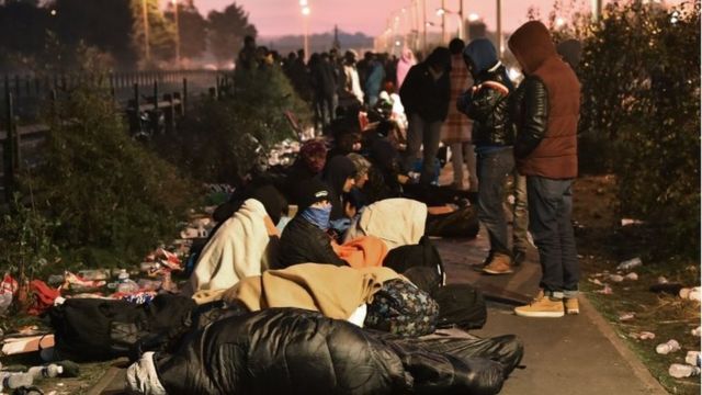 移転先を登録する窓口の前で夜を過ごした移民たち（27日）