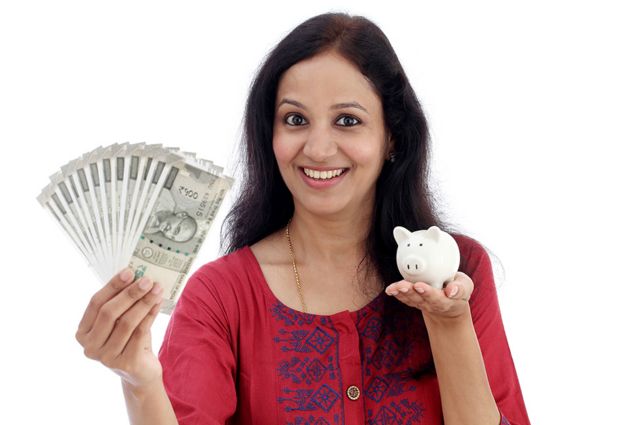An Indian woman holds money in one hand and a piggy bank of coins on the note