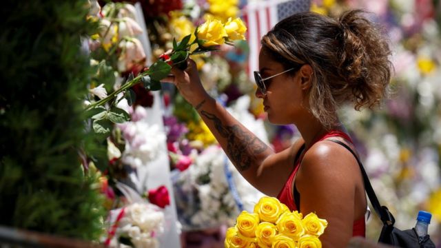 A woman mourns at a memorial site created by residents in front of a partially collapsed building in Surfside, Florida, 3 July 2021