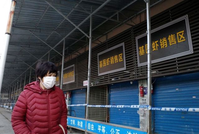 Mulher passa em frente ao Mercado Atacadista de Frutos do Mar de Huanan, na cidade chinesa de Wuhan
